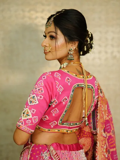 A side view of the bride's traditional Gujarati look, showing off her elegant backless blouse and the beautifully crafted floral bun.