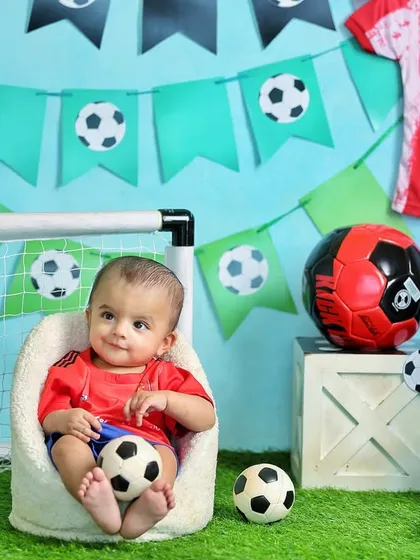This little guy is ready for the game in his football-themed sitter session. The props and backdrop create a fun and sporty atmosphere.