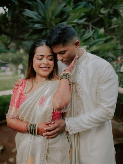 A tender moment captured during an outdoor engagement shoot. The groom gently caresses her face as they share a quiet, loving embrace amidst lush greenery.