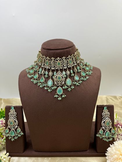 A heavy bridal choker set in a stunning emerald green. This design features multiple layers of stones and bead droppings, complete with matching oversized earrings, making it a comprehensive offering for your bridal customers.