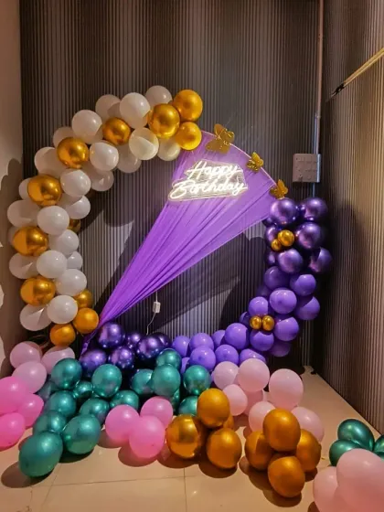 This photo shows the full corner setup with additional balloons on the floor in shades of teal, pink, and gold, adding more color to the party space.