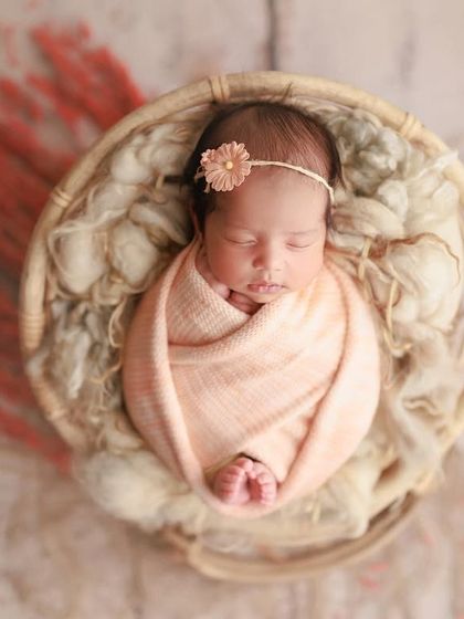 I love this peach setup. The soft wrap and delicate floral headband create a warm and gentle look for this sleeping beauty in a round basket.