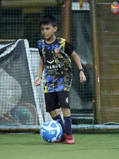 A young player focuses on the ball, ready to execute a pass or a dribble.