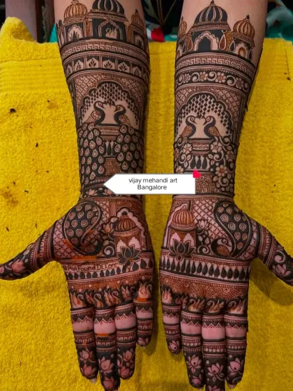 A classic and symmetrical full-hand bridal design. This style features traditional Rajasthani elements like palace architecture, facing peacocks, and lotus flowers, creating a timeless and royal look for your wedding day.