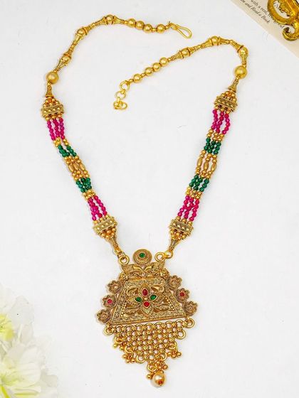 This flatlay of a traditional gold necklace includes soft floral props to add a touch of elegance. It's a great way to style ethnic jewellery for a modern audience.