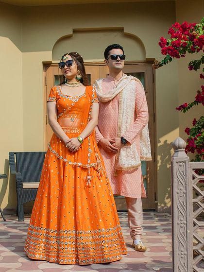 A stylish portrait of the couple in their coordinated Mehendi outfits, looking cool and confident in their sunglasses.