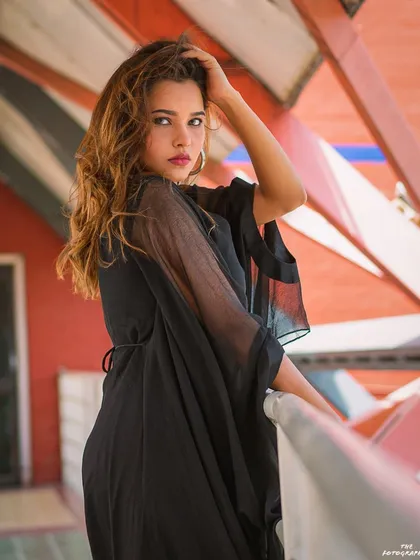 An outdoor fashion shot against a modern architectural background. The natural light and strong lines create a clean and stylish portrait.