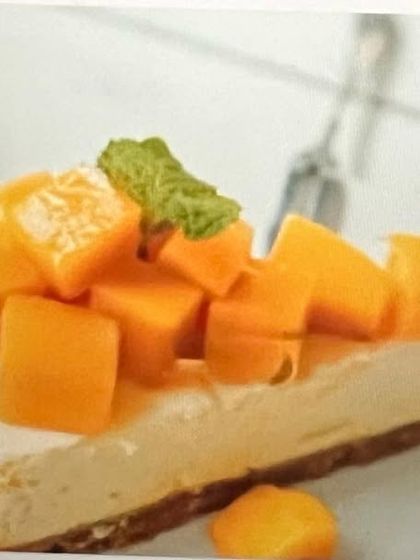 A professional shot of my plant-based mango cheesecake. You can see the creamy texture of the cashew-based filling and the generous topping of fresh mango chunks on a wholesome nutty crust.