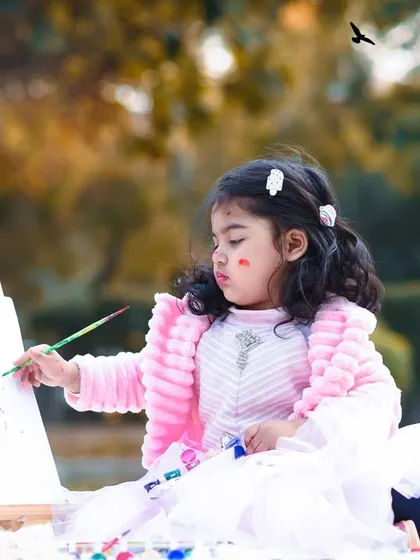 For older kids, an outdoor painting session is a wonderful theme. Here, a little artist is focused on her masterpiece in the park.