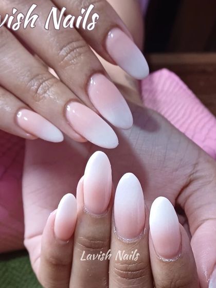 A soft and subtle ombre or Baby Boomer effect on long, almond-shaped nail extensions.