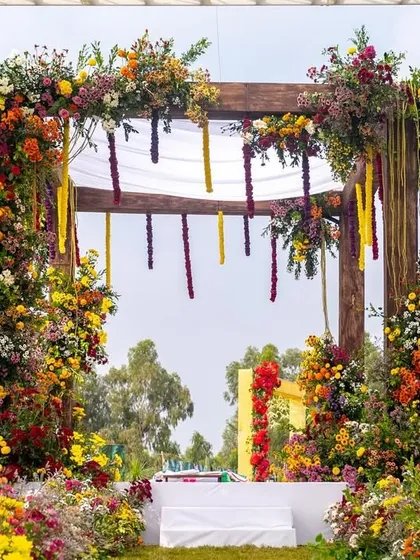 A view of the floral mandap from the guest's perspective, with a pathway lined with colorful blooms leading to the main stage.
