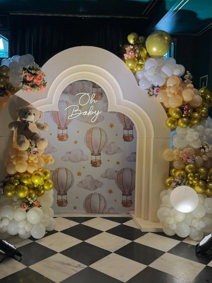 This 'Oh Baby' photo booth combines a hot air balloon motif with the classic teddy bear theme. The checkered floor and neutral gold and white balloon garlands add a touch of timeless elegance.