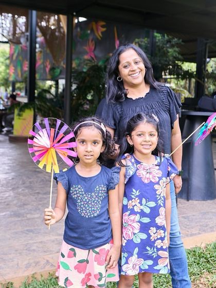 A mother posing with her two daughters, who are having a great time with their colorful pinwheels. It's a perfect family day out.