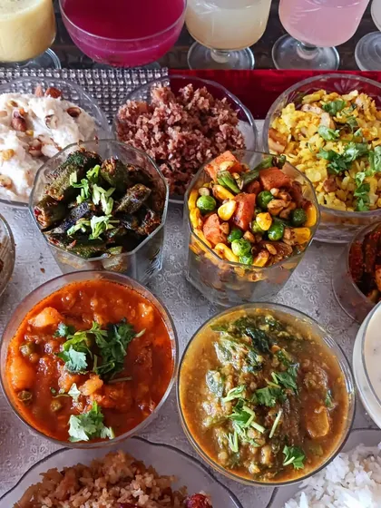 An assortment of vibrant vegetable dishes and pickles from the 56 Bhog spread. You can see preparations like bhindi, mix veg, and palak dal, showcasing a rainbow of flavours.