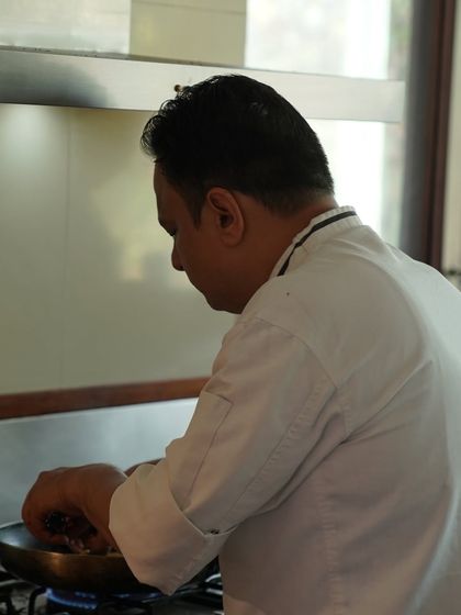 A chef in the kitchen, focused on preparing a dish. Our 'Easy Dining' service allows our chefs to bring their expertise directly into your home.