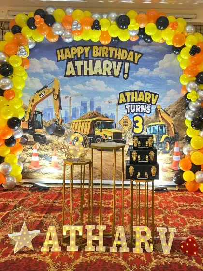 For kids who love big machines, this construction theme is a hit. I designed a full-stage setup for Atharv's 3rd birthday with a vibrant backdrop of diggers and trucks, a yellow, black, and orange balloon arch, and themed cake stands.