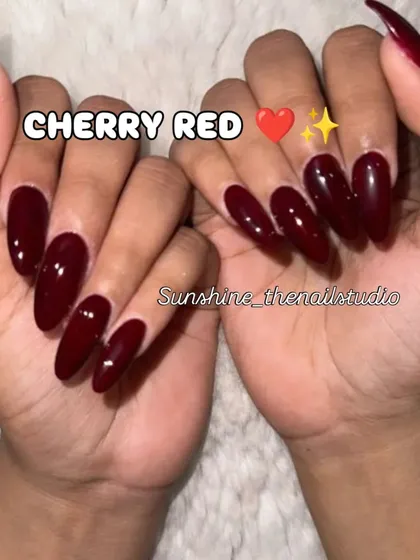 A classic set of long, almond-shaped nails in a glossy cherry red.