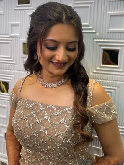 A beautiful, smiling Sangeet bride. Her off-shoulder sequin gown is paired with a soft smokey eye, a nude lip, and gentle waves in her hair.