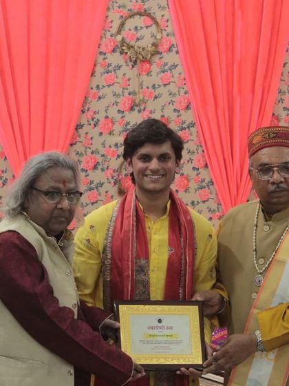 A young performer proudly displaying his award, flanked by senior artists.