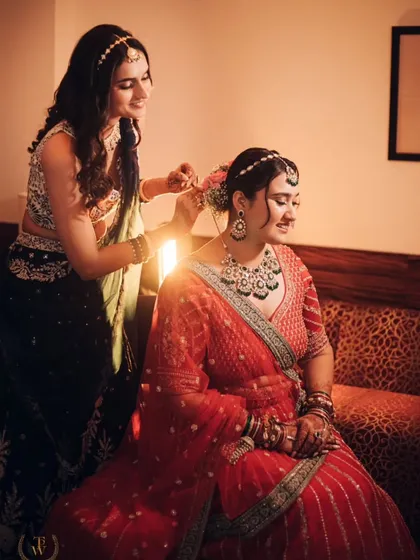 A happy, candid moment as Revati gets her hair done. The backlighting creates a beautiful glow, highlighting the joy and excitement of the preparations.