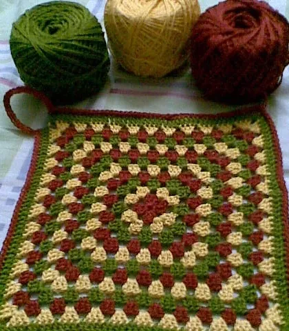 A classic granny square dishcloth with its corresponding yarn balls.