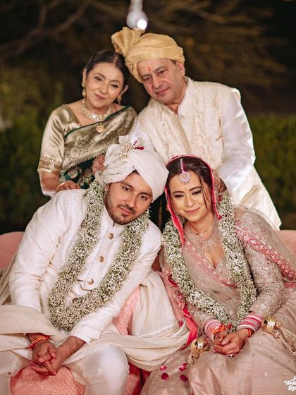 A heartwarming family portrait with the couple and their parents, a cherished memory from the wedding day.