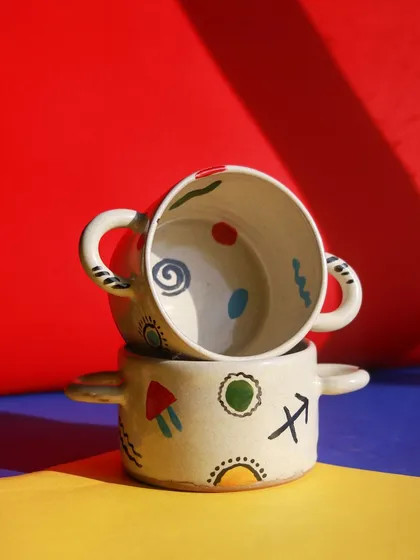 Two stacked bowls with handles from the 'Playful Mornings' collection, showcasing their bright, playful patterns and functional design.