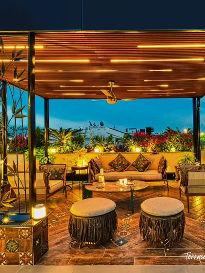 A close-up of the lounge area, designed to feel luxurious and artistic. The combination of patterned floor tiles, rustic stools, and warm overhead lighting creates an inviting atmosphere for evening gatherings.