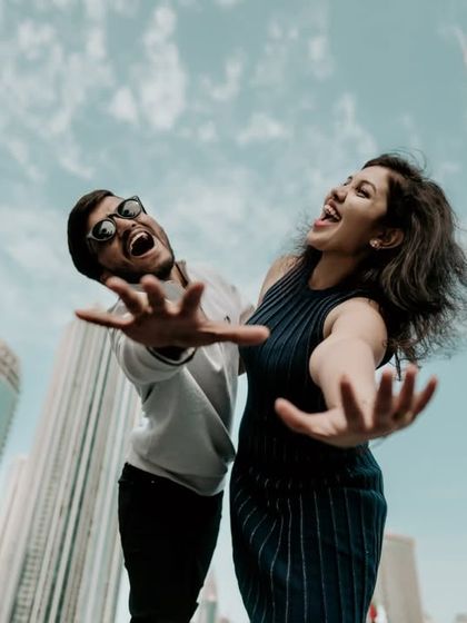 A fun and energetic shot with the couple reaching out towards the camera in front of the Burj Khalifa.
