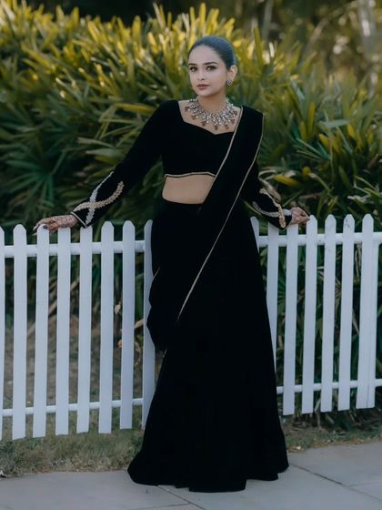 A modern and elegant look. The client pairs her custom black velvet lehenga saree with a sleek hairstyle and minimal jewelry.
