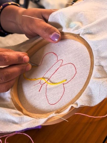 Starting a new punch needle project with the first few stitches. This participant is outlining a butterfly design with yellow yarn, the beginning of a beautiful piece.