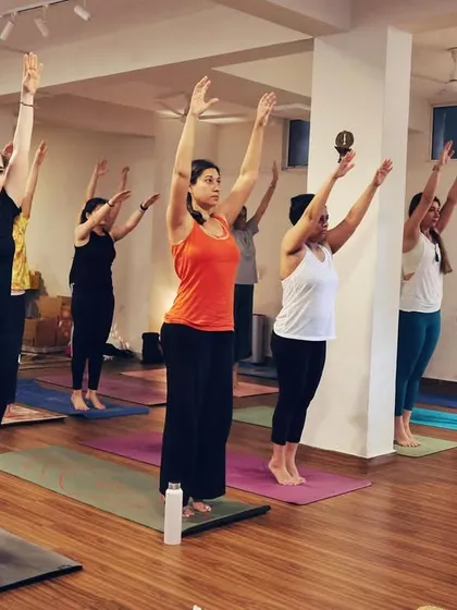 The class moves in unison through a part of the Suryanamaskar (Sun Salutation) sequence. This synchronized movement builds a powerful collective rhythm and focus.