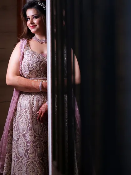 A candid shot of the bride, peeking from behind a corner. Her soft smile and glowing makeup create a beautiful, artistic photo.
