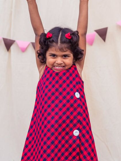 A joyful leap in a red and blue checkered dress. The sleeveless A-line design is perfect for warm weather and non-stop fun.