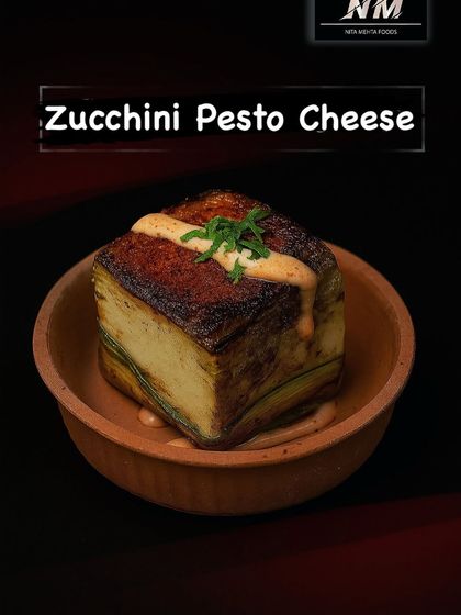 An elegant Italian-inspired appetizer. This is our Zucchini Pesto Cheese, featuring layers of grilled zucchini and creamy pesto paneer, served in a traditional earthenware bowl.