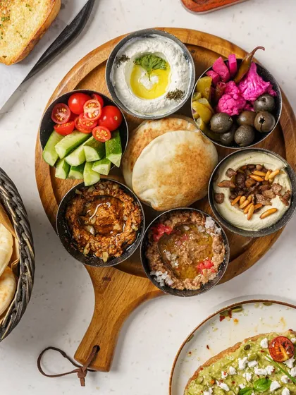 A Middle Eastern breakfast platter shot from above. This image showcases the variety of dips, salads, and fresh pita bread, making it look like a vibrant and healthy way to start the day.