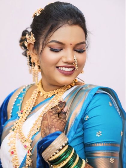 A happy bride in a white and blue saree. I created a look with winged eyeliner and a warm smile, perfect for her special day.
