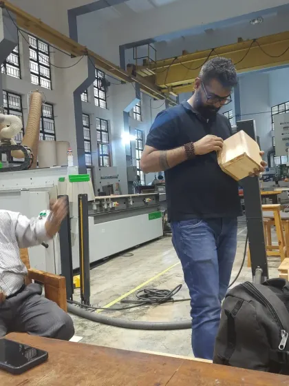 A student proudly inspects his finished box while discussing the process with an instructor. This moment captures the satisfaction of completing a project from start to finish.
