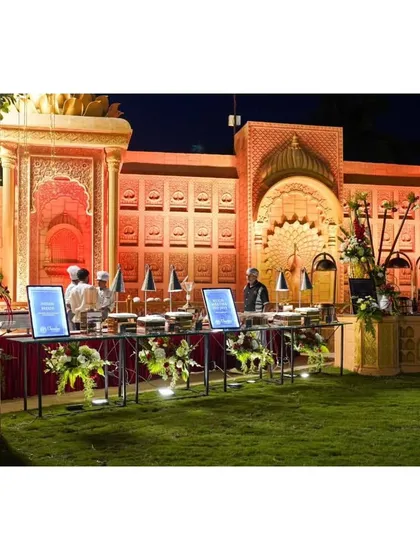 A grand buffet setup against an ornate, palace-themed backdrop. The lighting highlights the intricate carvings, making the food display feel like part of a royal feast.