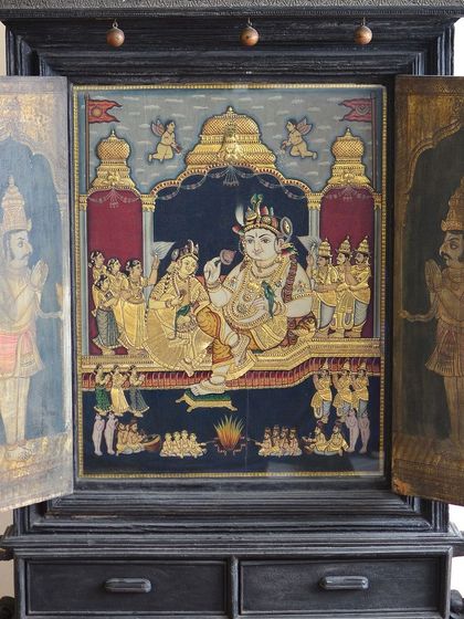 A masterpiece from our collection: a travelling temple of Radha and Krishna from the late 19th century. This portable marvel, featuring a Tanjore painting of Lord Krishna, once graced devotional gatherings, capturing the essence of artistry and tradition.
