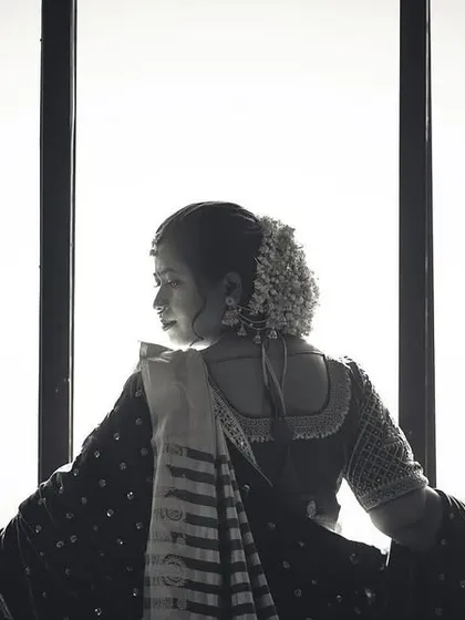 A beautiful and contemplative black and white shot of a bride looking out a window from behind. The bright light creates a strong silhouette, evoking a sense of looking towards the future.