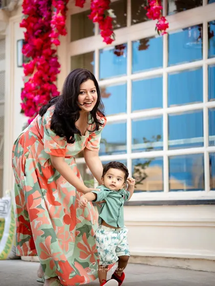 A mother helps her son take his first steps, a precious milestone captured during their family lifestyle shoot.