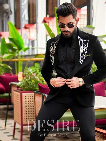 Adjusting the fit of the black velvet blazer. This shot highlights the geometric embroidery on the lapels and the luxurious texture of the fabric.