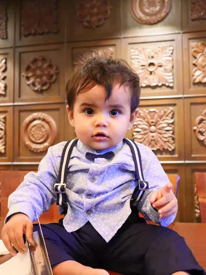 A full-length shot of my nephew sitting on a table during his first birthday celebration. The carved wooden background adds a lovely texture to this formal yet candid baby portrait.