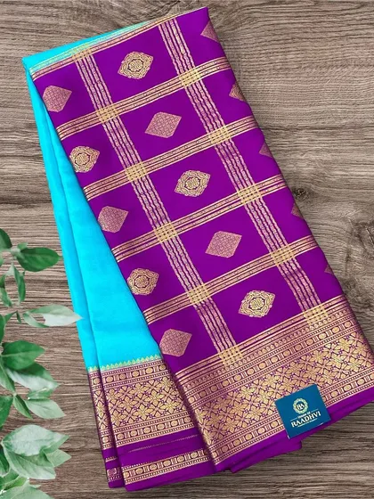 A striking half-and-half pure Mysore crepe silk saree combining a sky blue body with a purple pallu and gold zari work.