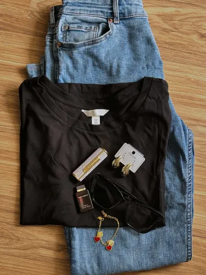 Getting ready for a meeting doesn't always require a suit. A simple black t-shirt and blue jeans, accessorized with gold jewelry and classic sunglasses, can look both professional and stylish.