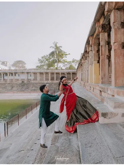 A playful moment on the steps of a temple tank, with the groom helping his bride-to-be.