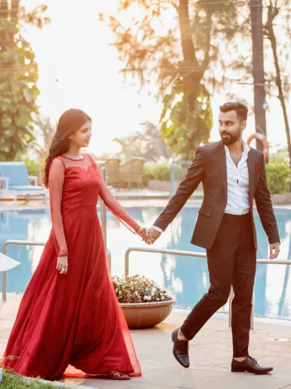 A stylish pre-wedding shot of a couple walking hand-in-hand by a resort pool, capturing a chic and relaxed moment.