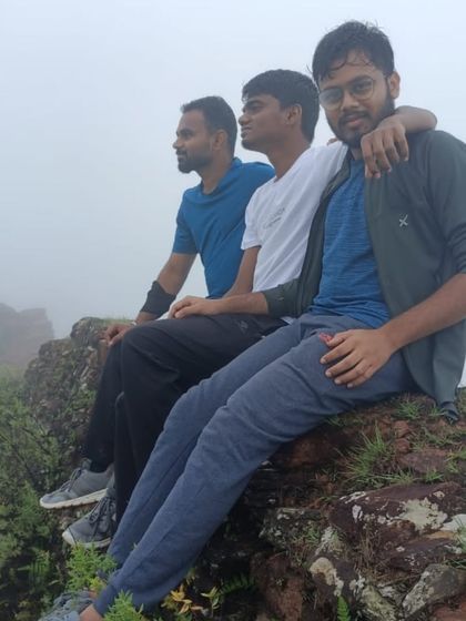 A group of friends sitting on a rocky outcrop, taking a break and enjoying the misty view during the Bandaje Falls trek.