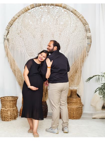 A quiet, tender moment captured from behind. The expecting mother leans on her partner's shoulder in our boho studio, creating a feeling of comfort and togetherness.